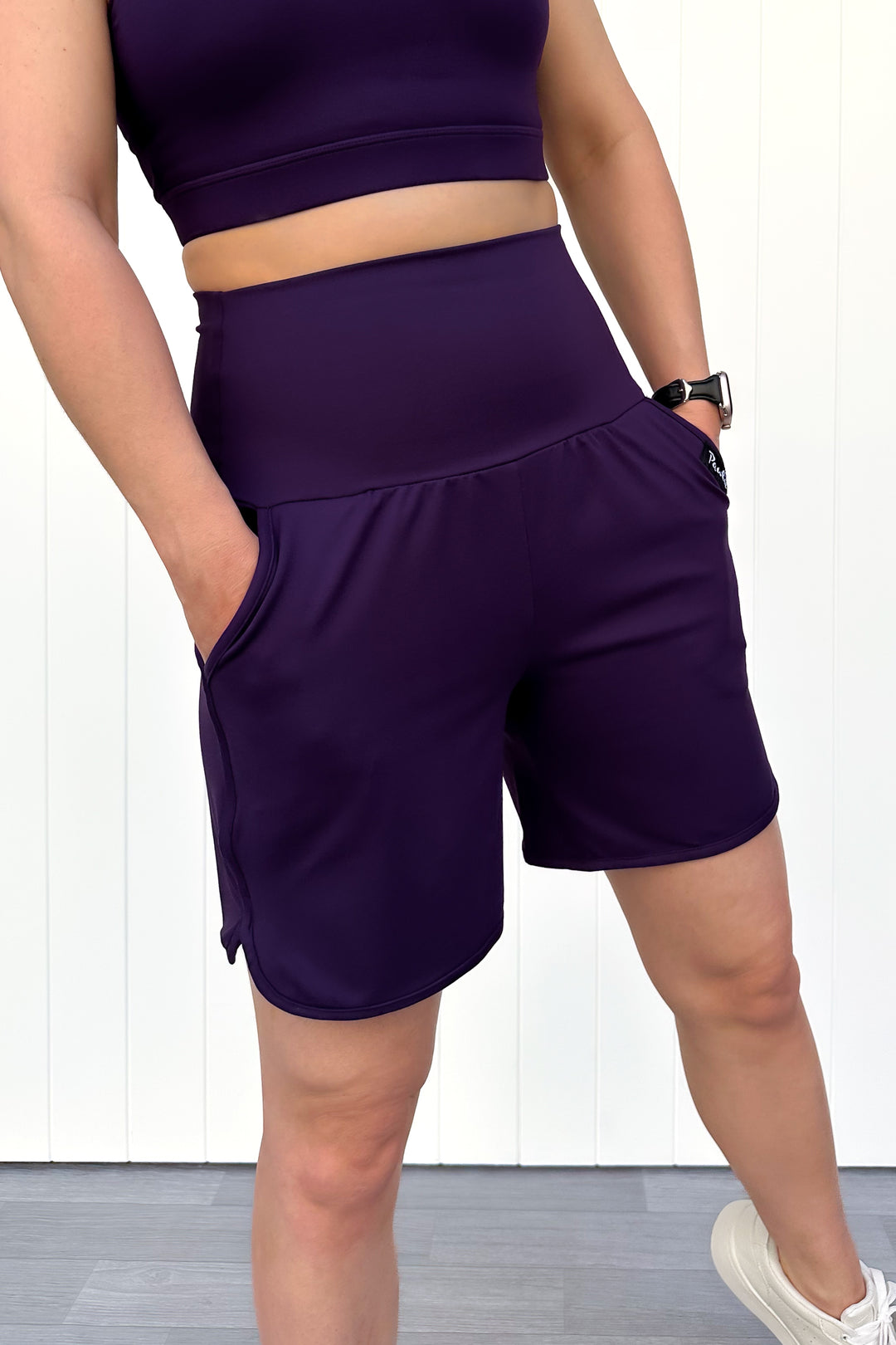 Person wearing purple athletic shorts and top on a white background
