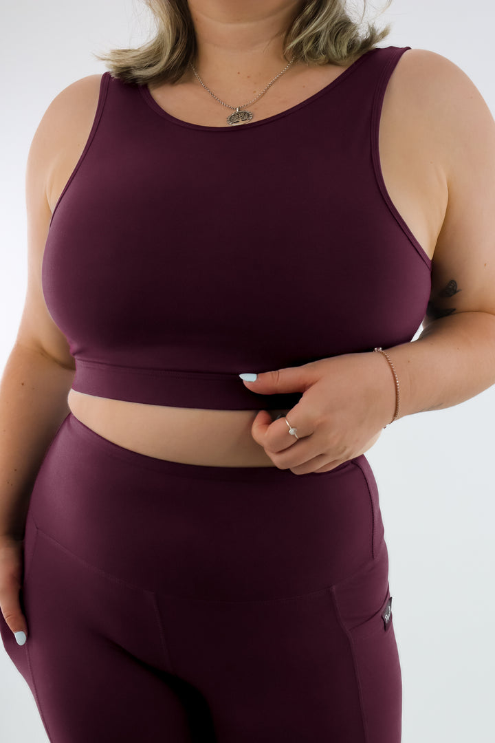 Person wearing a maroon sports bra and leggings set on a white background