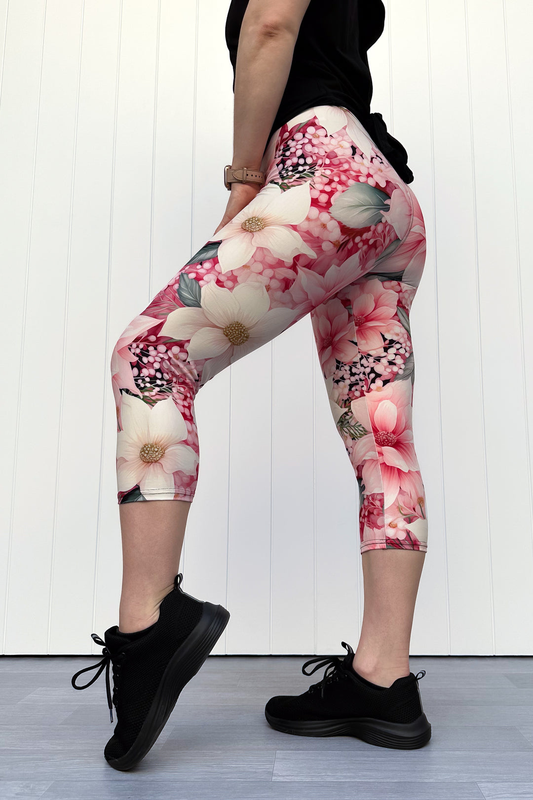 Person wearing pink and cream floral capri leggings standing in front of white background