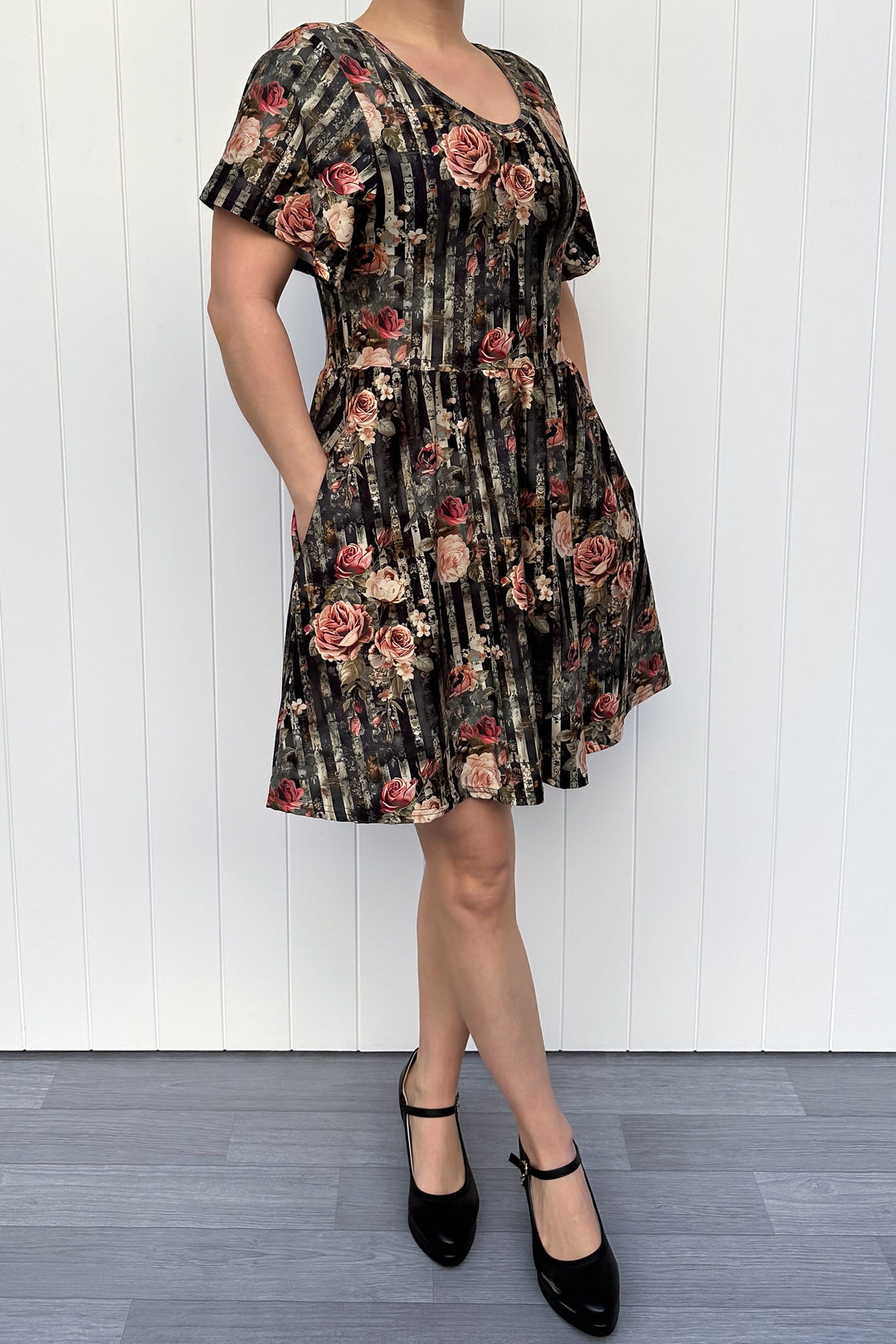Woman wearing a floral dress against a white wooden panel background