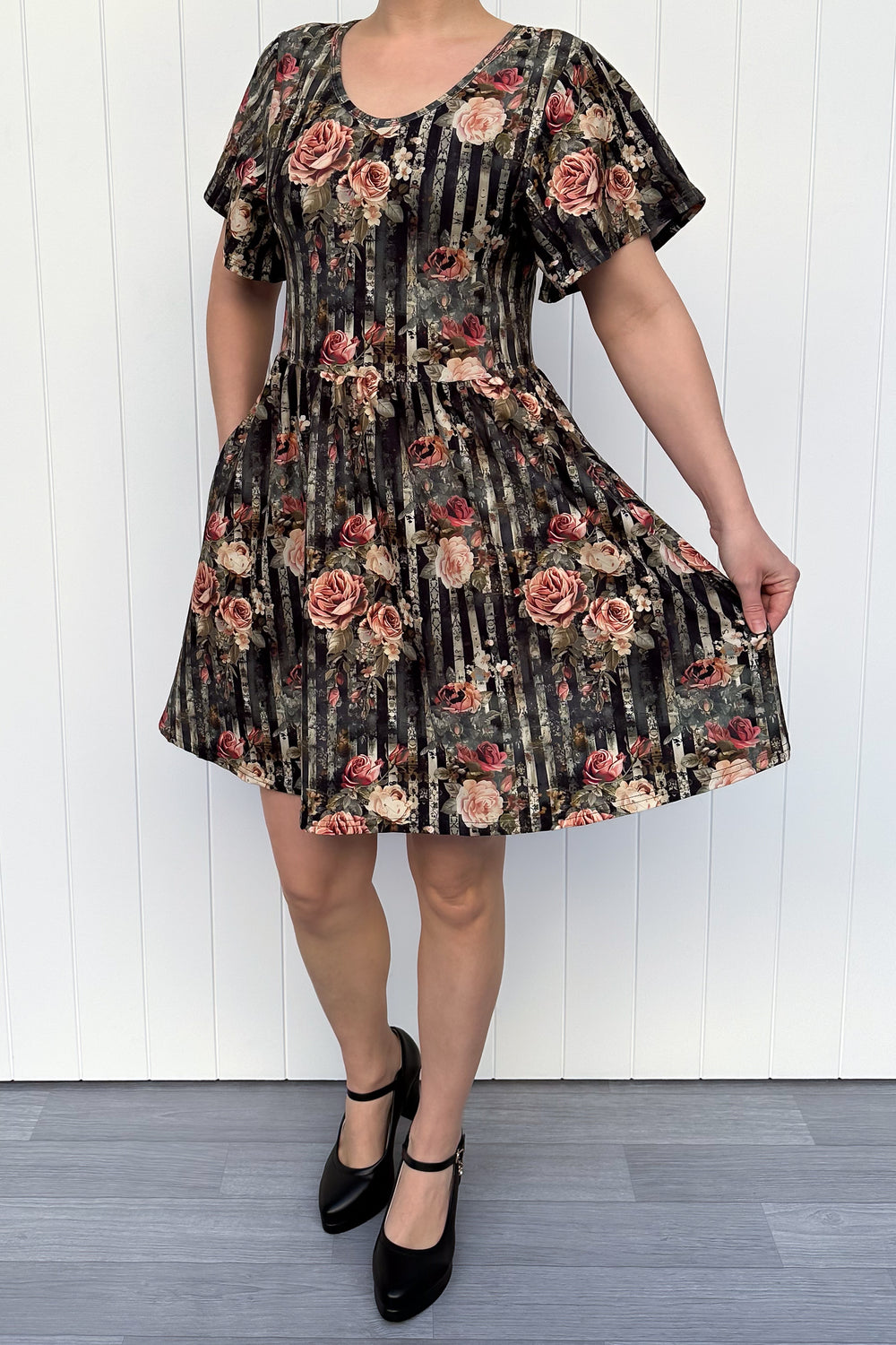 Person wearing a floral dress with a white wooden background