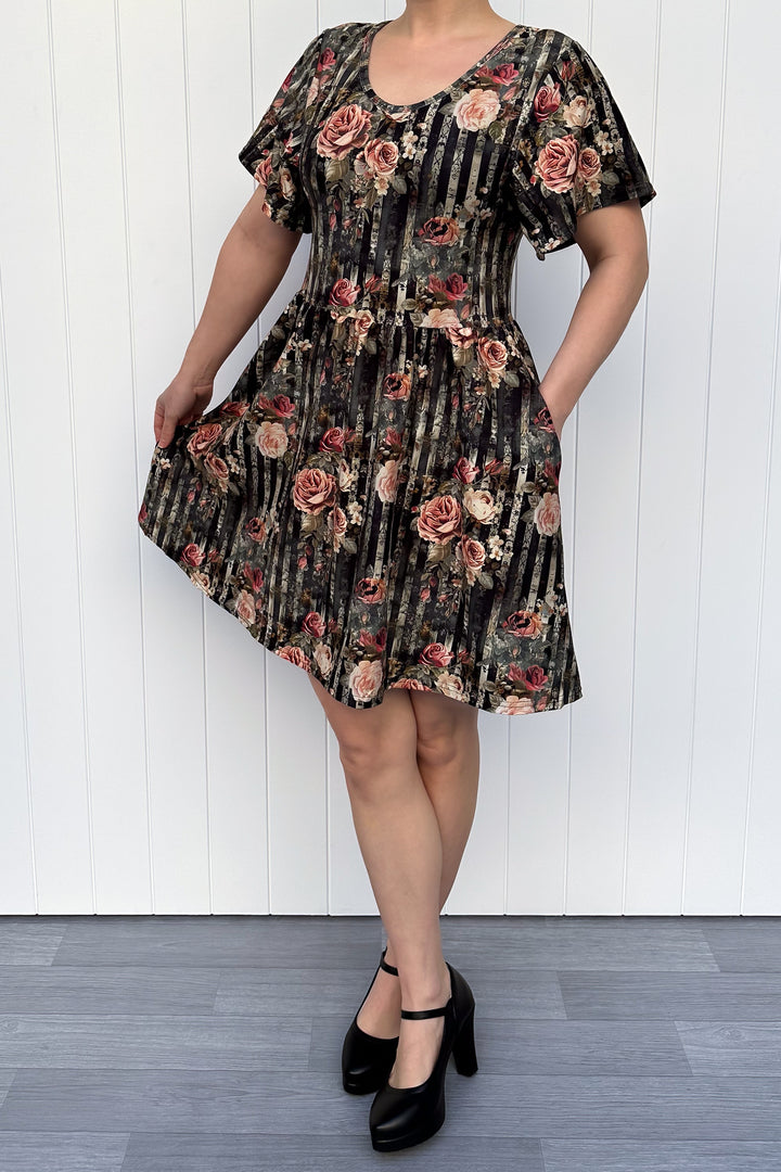 Person wearing a floral dress with a black and white striped pattern against a white wall.