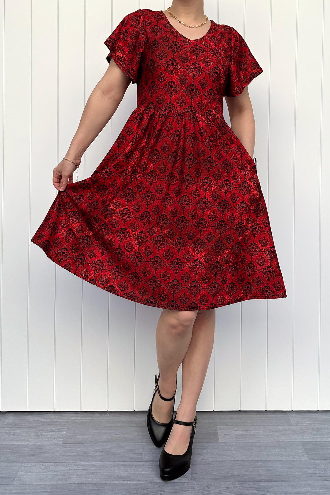 Red floral dress being twirled against a white wooden panel background