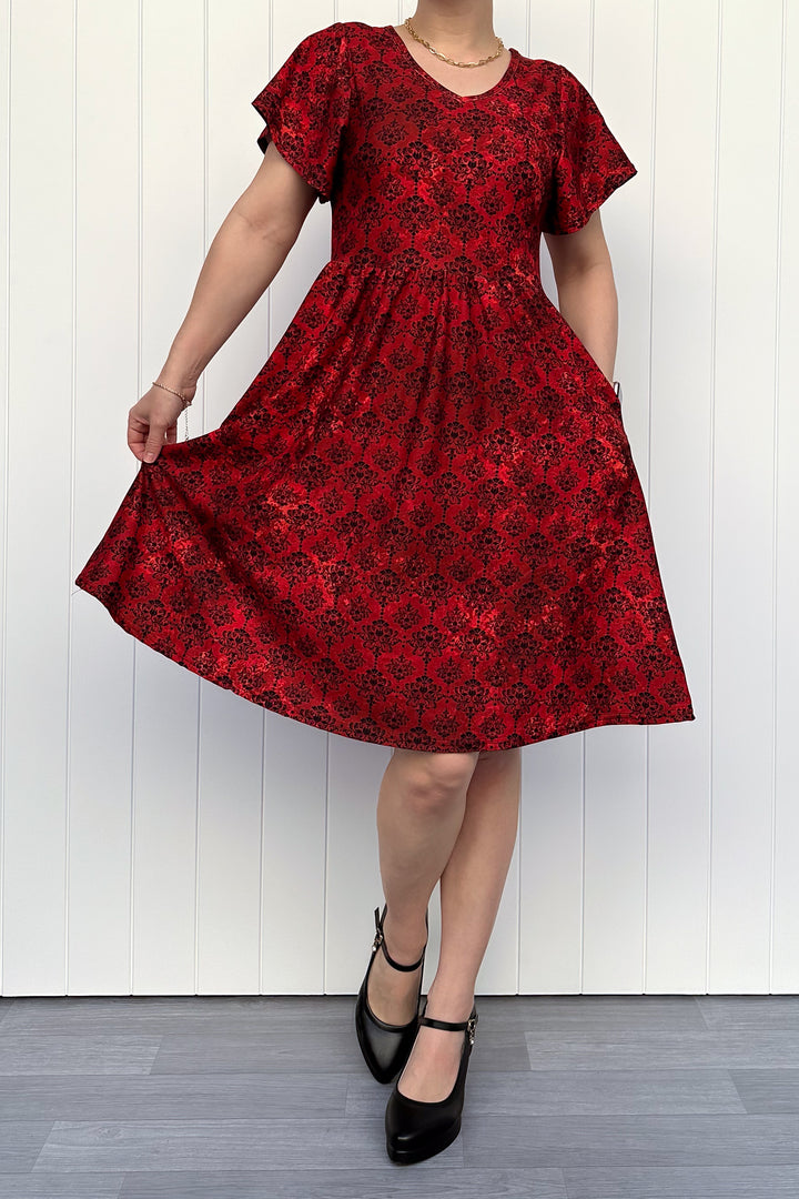 Red floral dress being twirled against a white wooden panel background
