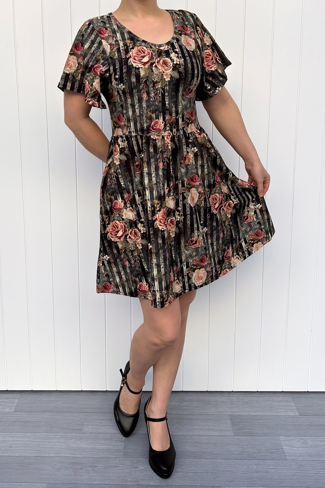 Woman wearing a floral dress against a white wooden panel background