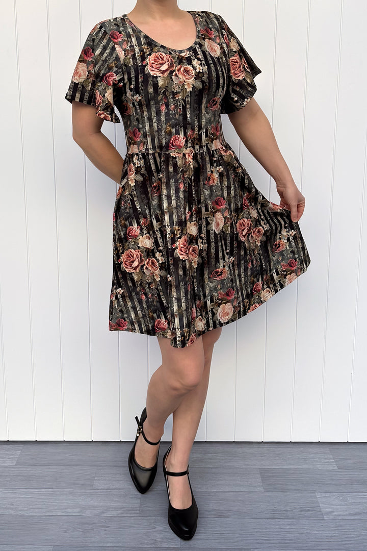 Woman wearing a floral dress against a white wooden panel background
