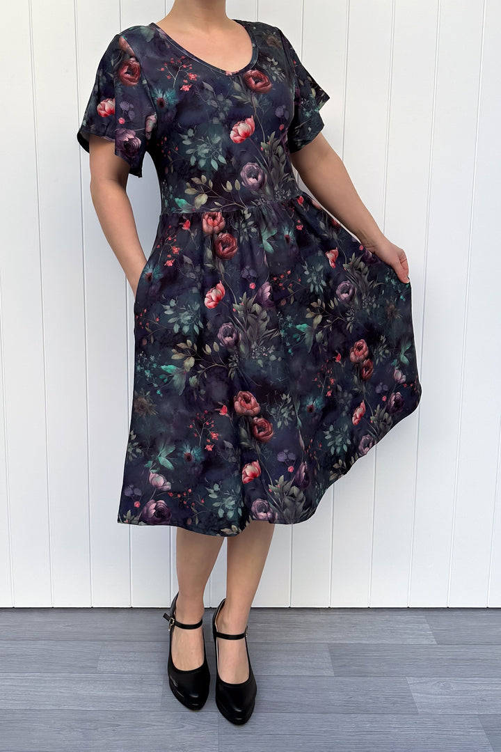 Woman wearing a floral dress against a white wooden panel background