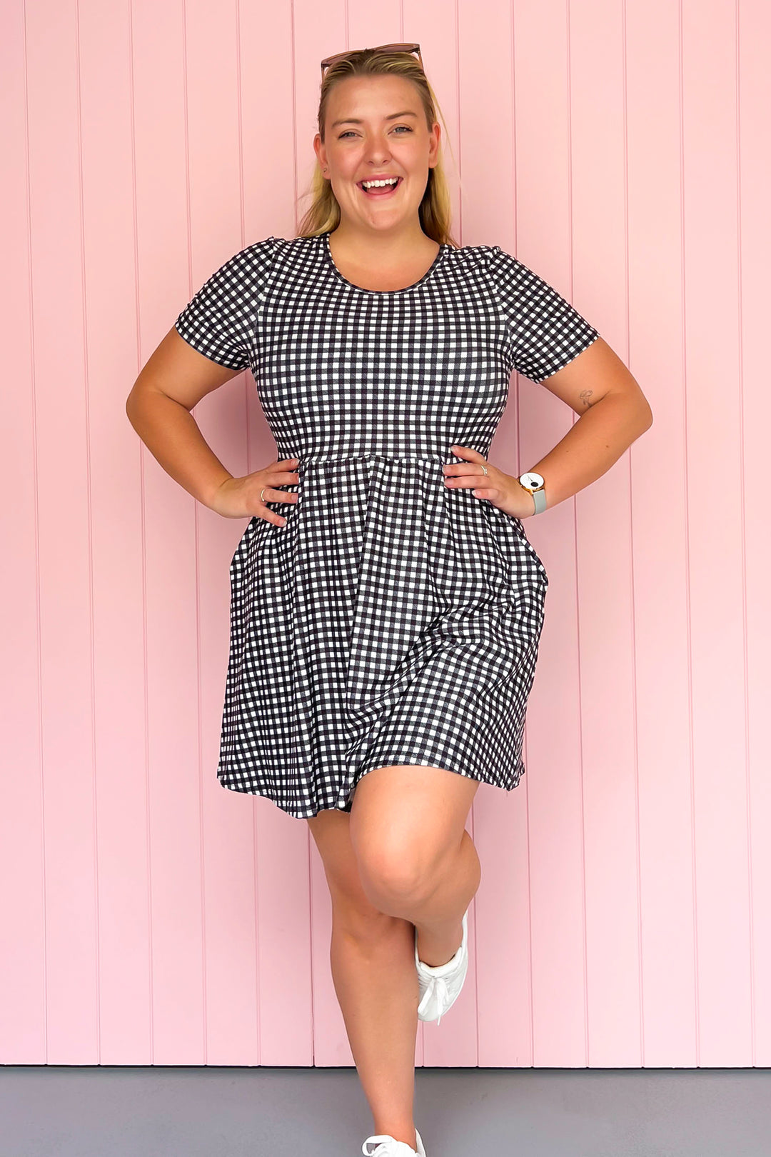 Woman wearing a black and white checkered dress against a pink wooden panel background